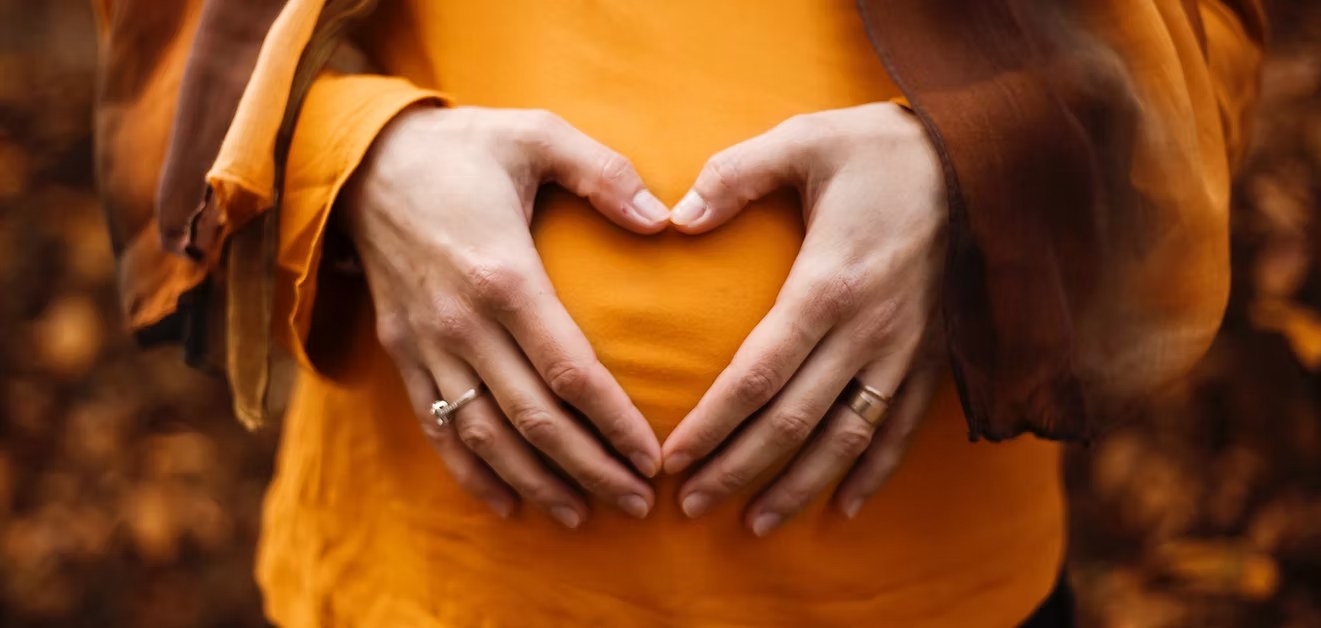 Expecting mother forming a heart with her hands